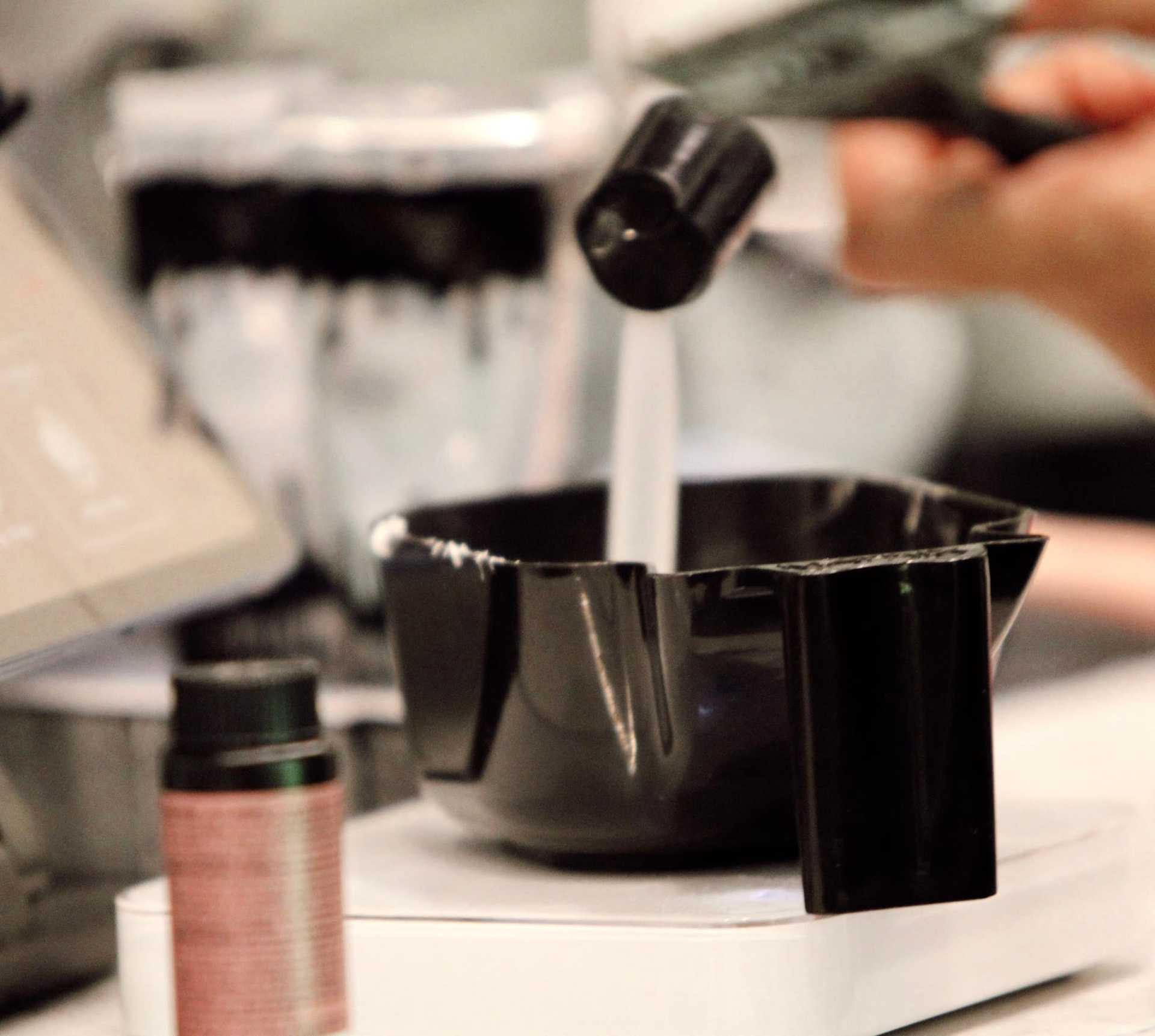 Hair dye being prepared in a black bowl at a salon.