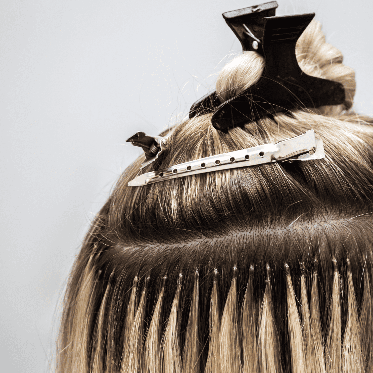 Hair extensions applied using clips and threading, shown on the back of a person's head.